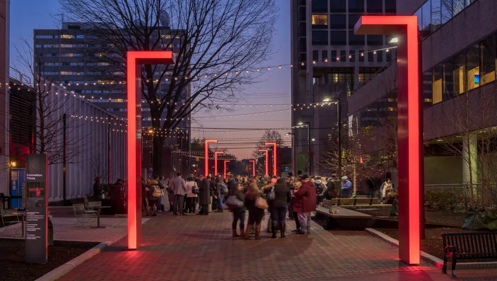 People stand and chat along innovation plaza at night