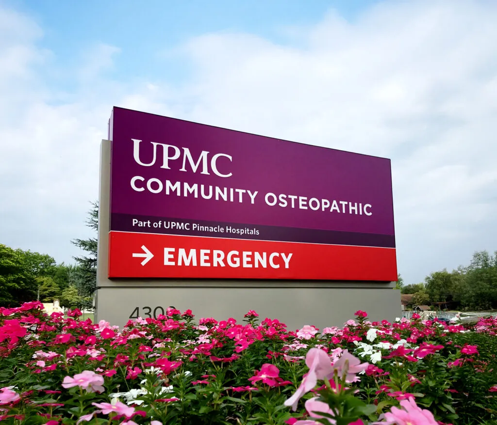 Community Osteopathic UPMC Sign sitting amongst a bed of flowers
