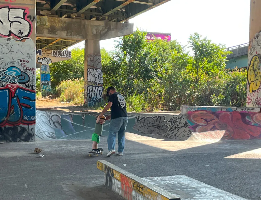 Brad teaching his son how to skateboard